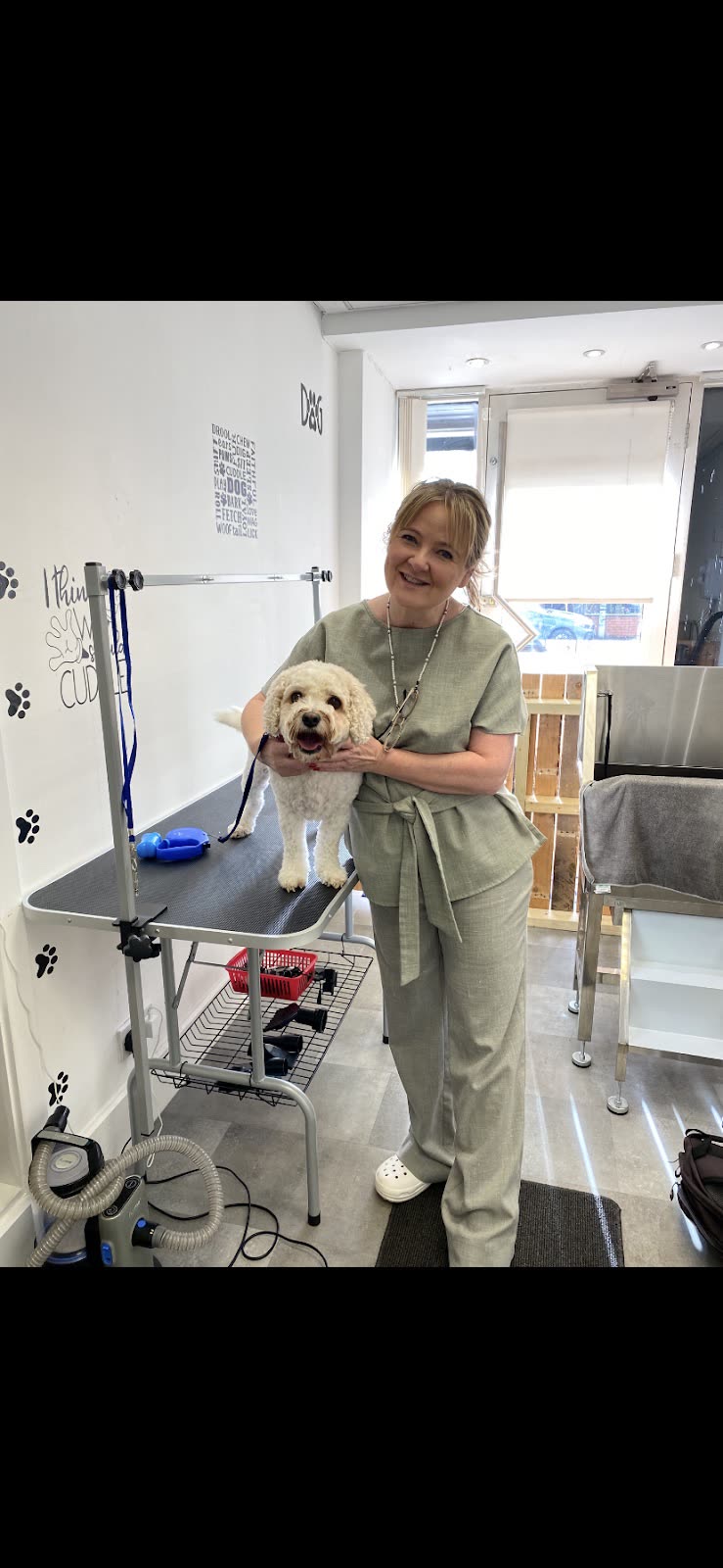 The groomer at the table with a small white dog after its groom
